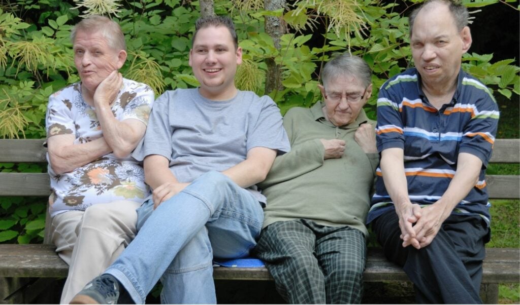 Four men on a bench, smiling.