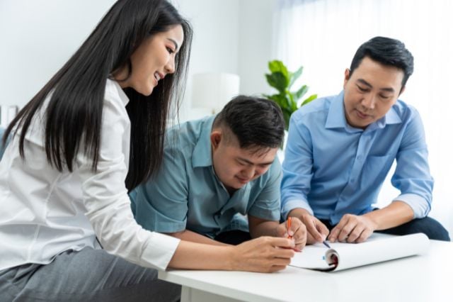 young man with down syndrome writing with parents 