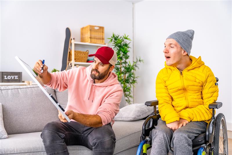 man in wheelchair looking at man with whiteboard