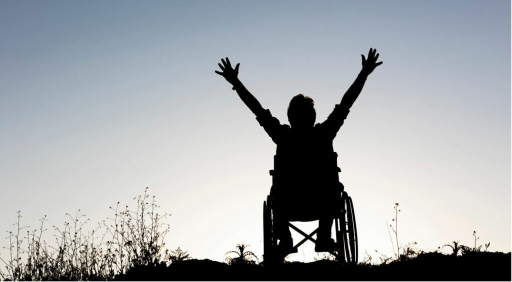Wheelchair user rejoicing in silhouette