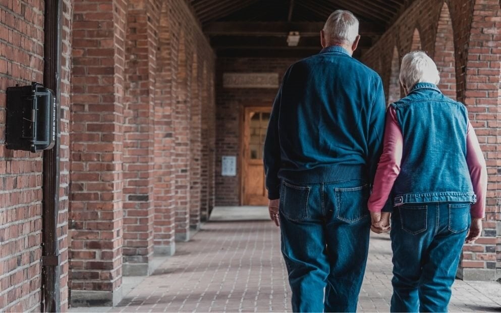 Elderly couple walking away, hand in hand.